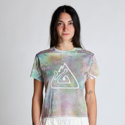 Person wearing a tie-dye t-shirt with a logo on a plain background
